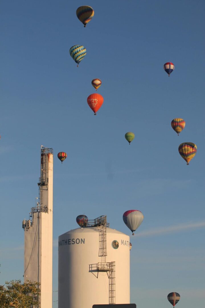 A group of hot air balloons flying over a factory